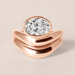 Top-down birds-eye view of Liora oval bezel engagement ring in 18K rose gold paired with a matching diamond contour band.