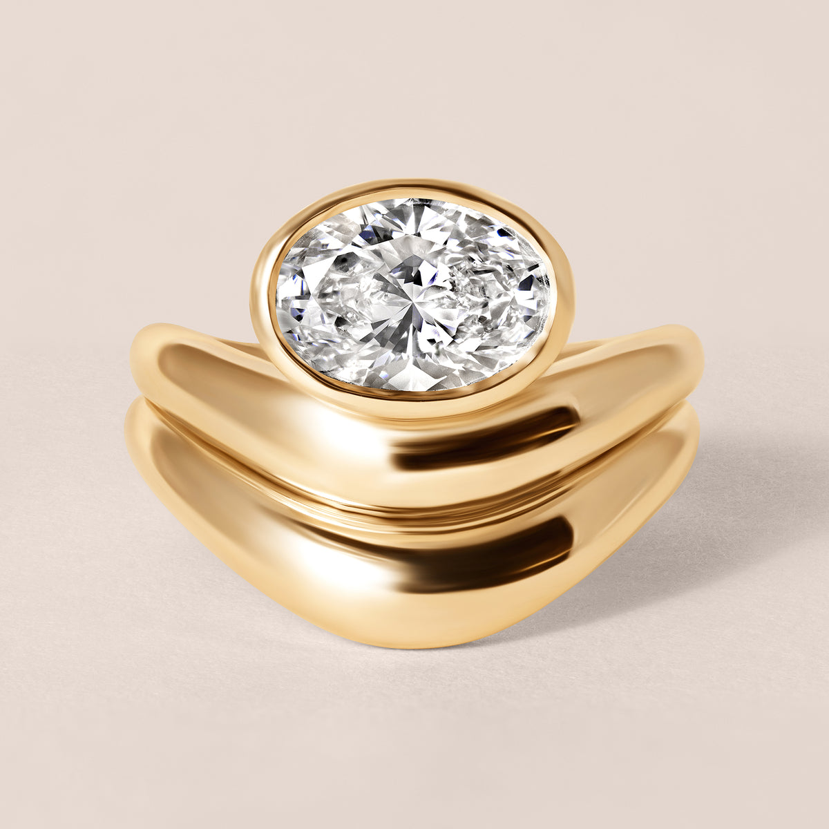 Top-down birds-eye view of Liora oval bezel engagement ring in 18K yellow gold paired with a matching diamond-set contour guard band.