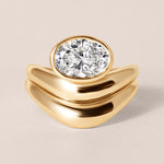 Top-down birds-eye view of Liora oval bezel engagement ring in 18K yellow gold paired with a matching diamond-set contour guard band.