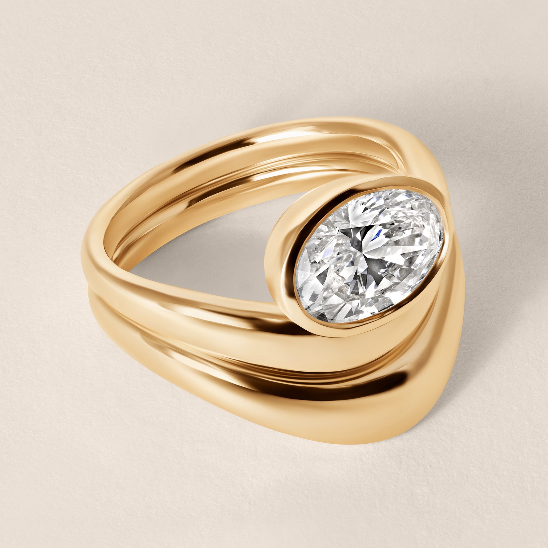 Three-quarter angled view of Liora oval bezel engagement ring stacked with a diamond contour wedding band in 18K yellow gold.