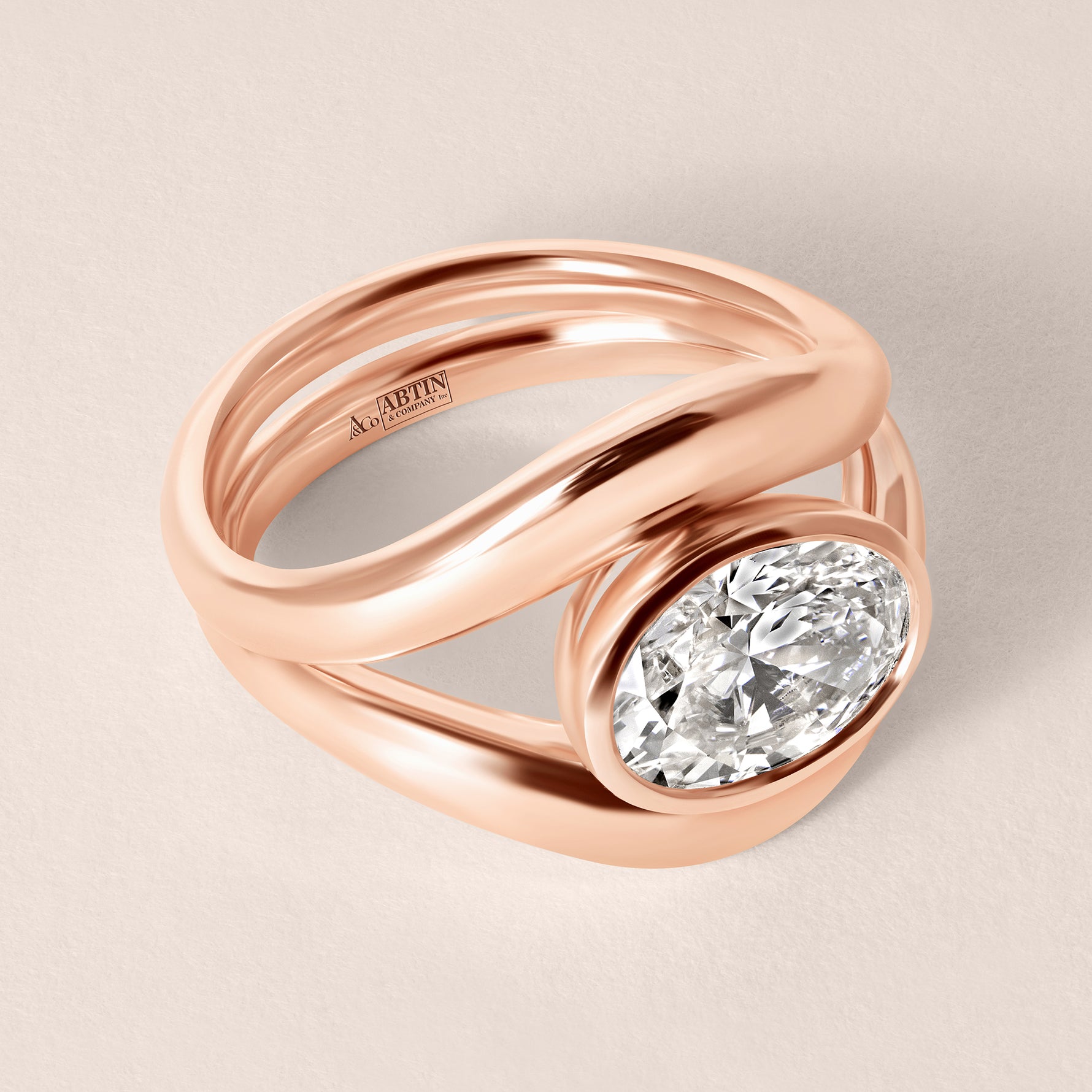 Three-quarter angled view of Liora oval bezel engagement ring stacked with a plain gold contour wedding band in 18K rose gold.