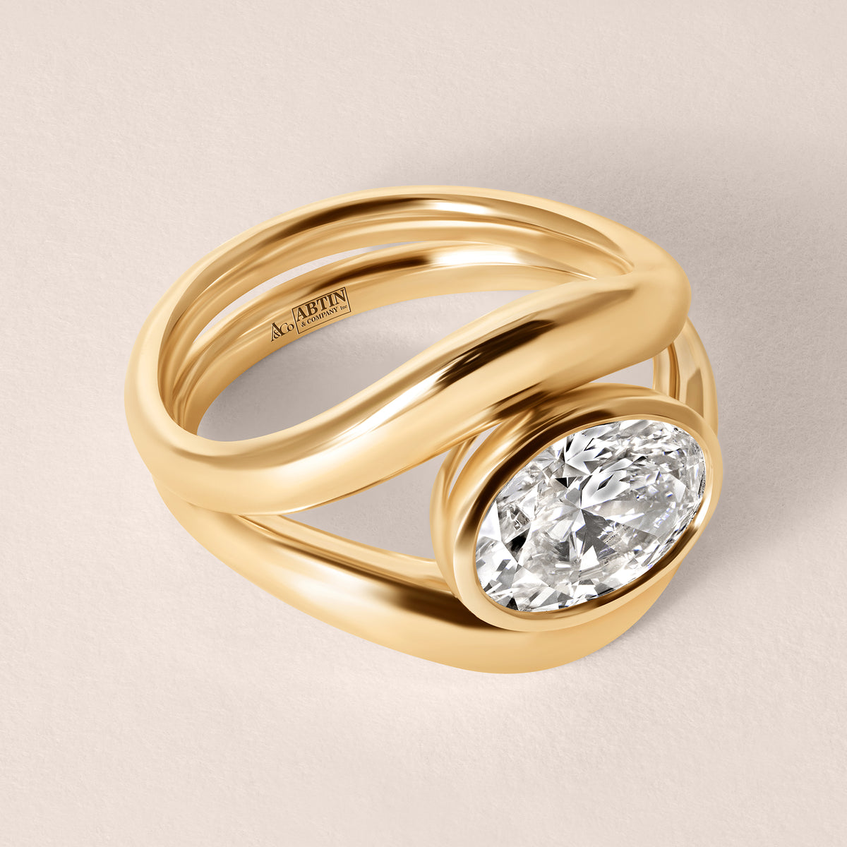 Three-quarter top view of Liora oval bezel engagement ring in 18K rose gold showing the elegant metal split-band design.