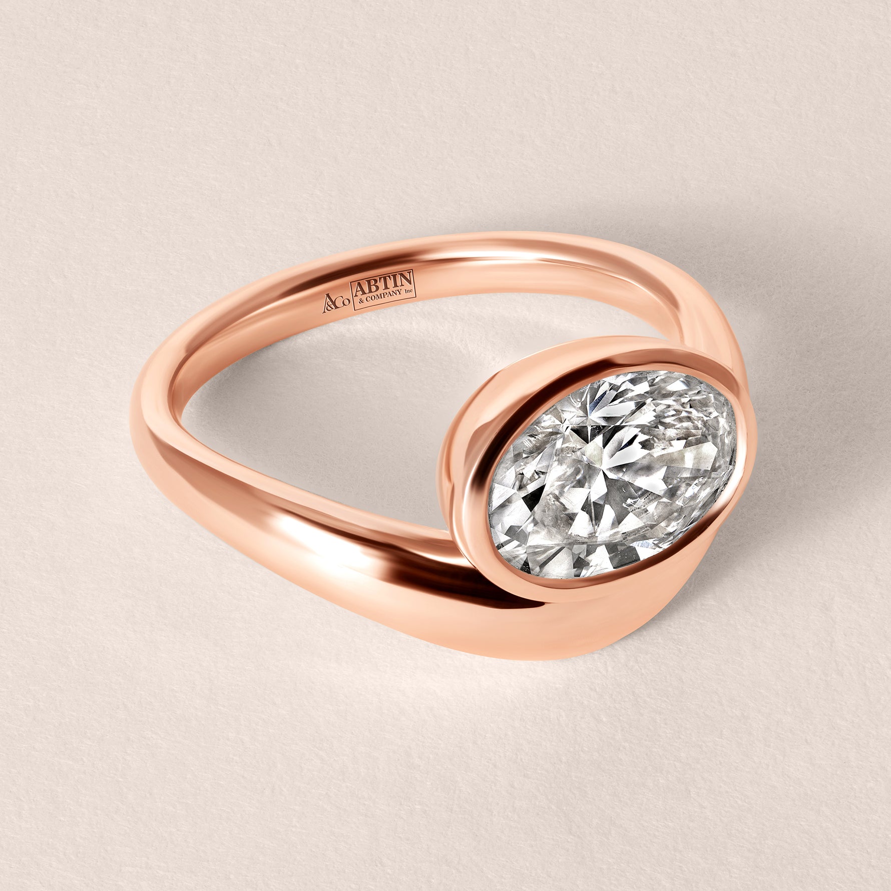 Three-quarter top view of Liora oval bezel engagement ring in 18K rose gold showing the elegant metal split-band design.
