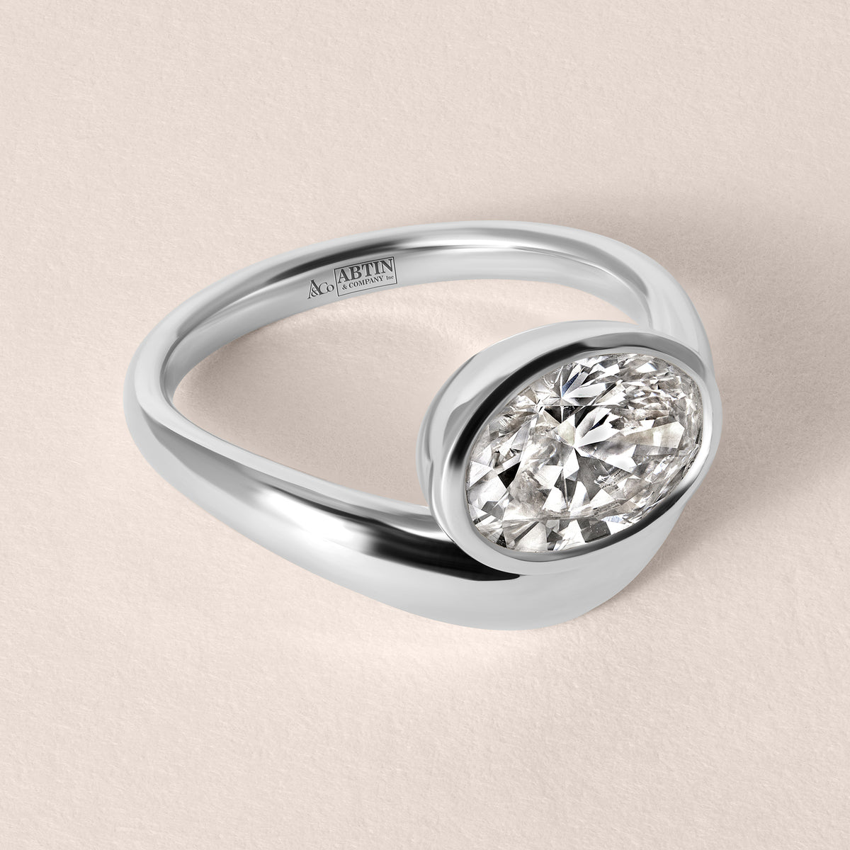 Three-quarter top view of Liora oval bezel engagement ring in white gold or platinum showcasing the fluid split-band shank.