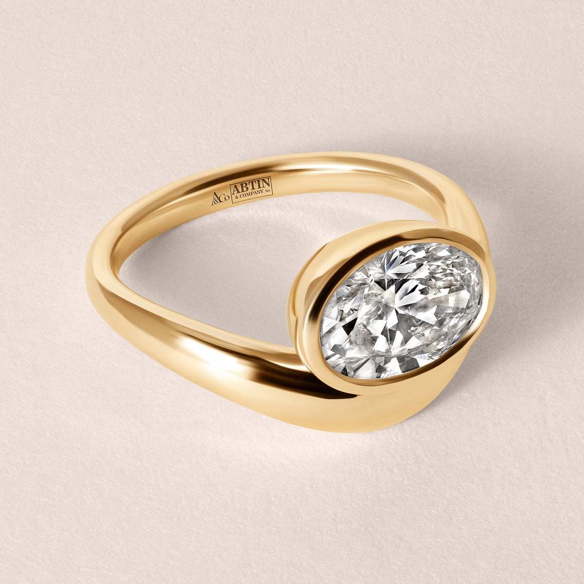 Three-quarter top view of Liora oval bezel engagement ring in 18K yellow gold showcasing the band curvature.